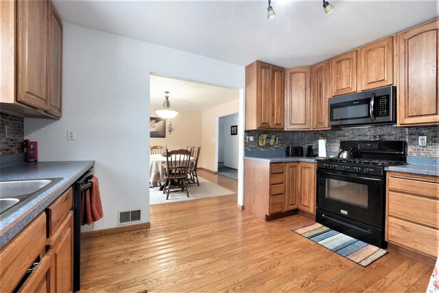 kitchen with tasteful backsplash, black appliances, and light wood-type flooring