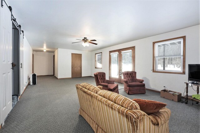 carpeted living room with a barn door and ceiling fan