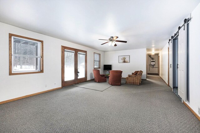 unfurnished living room featuring carpet, french doors, a barn door, and ceiling fan