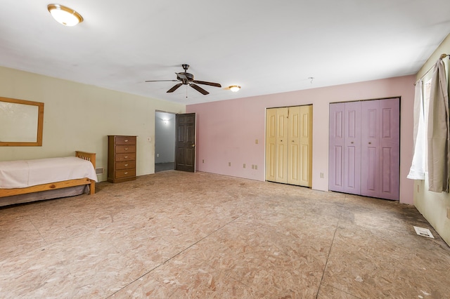 unfurnished bedroom featuring multiple closets and ceiling fan