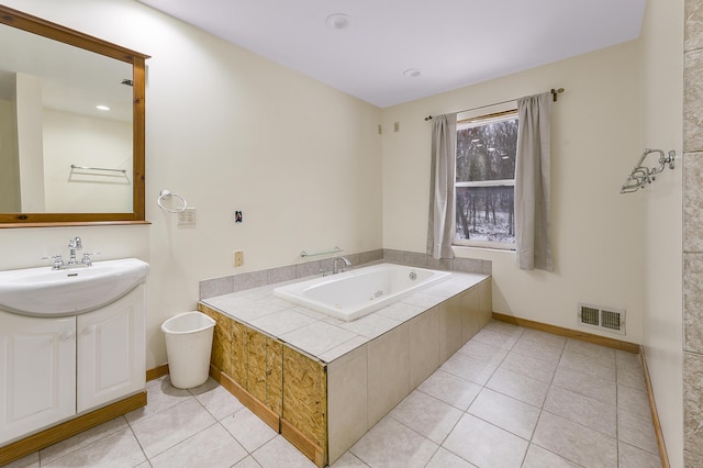 bathroom with tile patterned flooring, vanity, and tiled bath