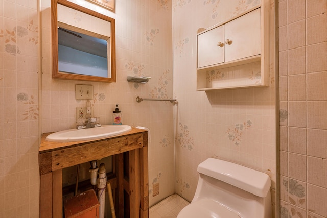 bathroom featuring sink, tile walls, and toilet