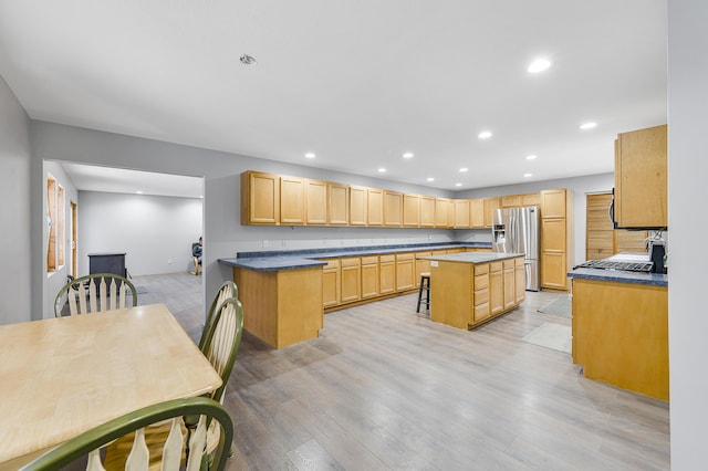 kitchen with stainless steel fridge with ice dispenser, light brown cabinets, light hardwood / wood-style flooring, and a kitchen island