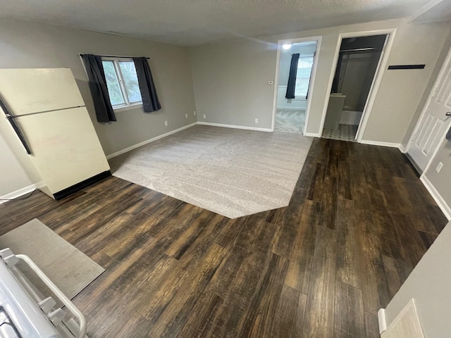 unfurnished living room featuring dark hardwood / wood-style flooring and a textured ceiling