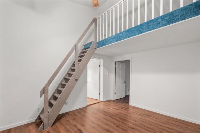 stairs with a high ceiling, baseboards, and wood finished floors