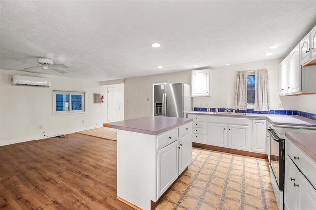 kitchen featuring stainless steel fridge, open floor plan, black range with electric stovetop, a center island, and a wall mounted air conditioner