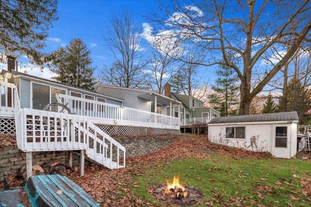 view of home's exterior featuring a fire pit, a chimney, stairway, an outbuilding, and a deck