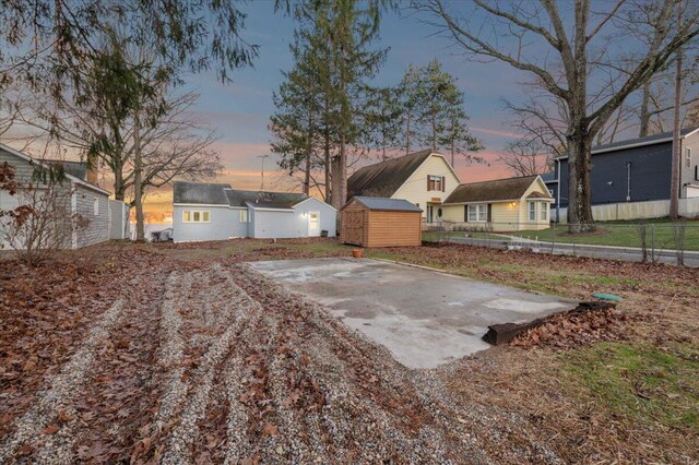 view of yard with driveway, fence, a storage unit, and an outdoor structure