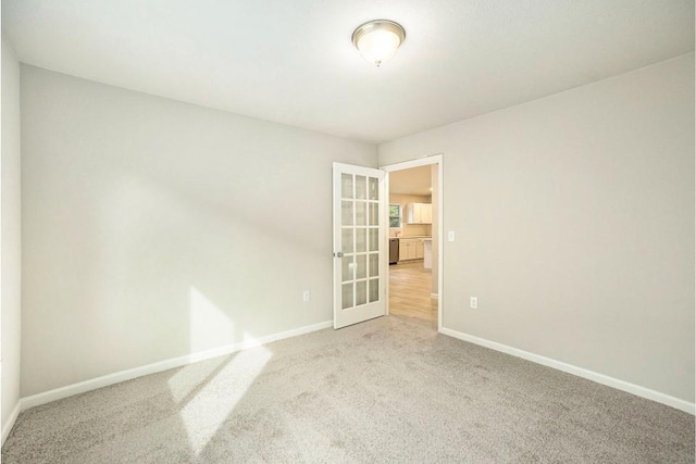 spare room featuring french doors and light colored carpet