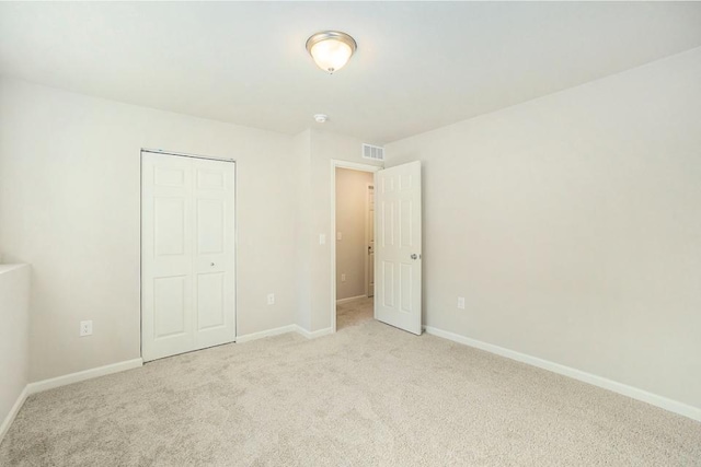 unfurnished bedroom with light colored carpet and a closet