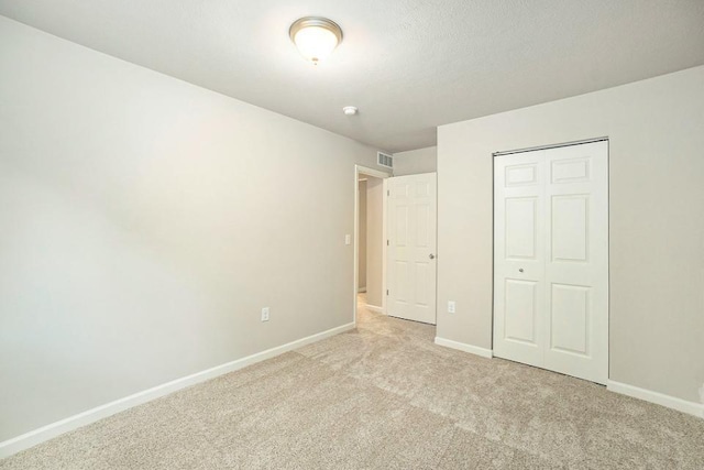 unfurnished bedroom with a closet and light colored carpet