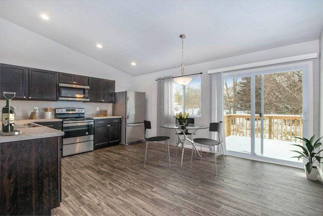 kitchen featuring dark brown cabinetry, stainless steel appliances, vaulted ceiling, decorative light fixtures, and dark hardwood / wood-style floors