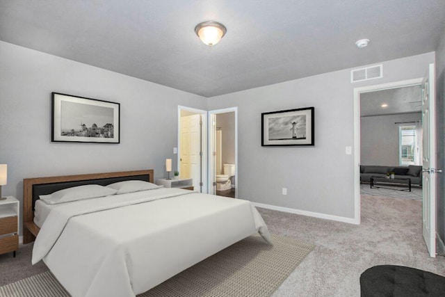 bedroom with connected bathroom and light colored carpet