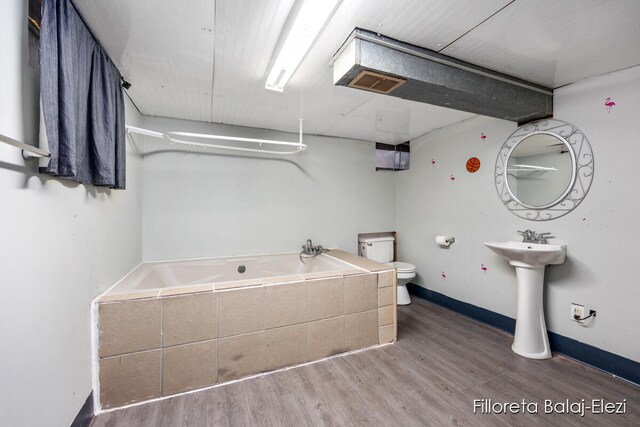 bathroom featuring hardwood / wood-style flooring, toilet, and a tub