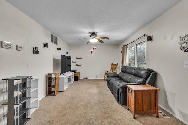 living room with a textured ceiling, carpet floors, and ceiling fan