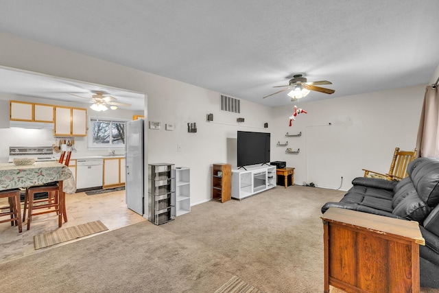 carpeted living room with ceiling fan and sink