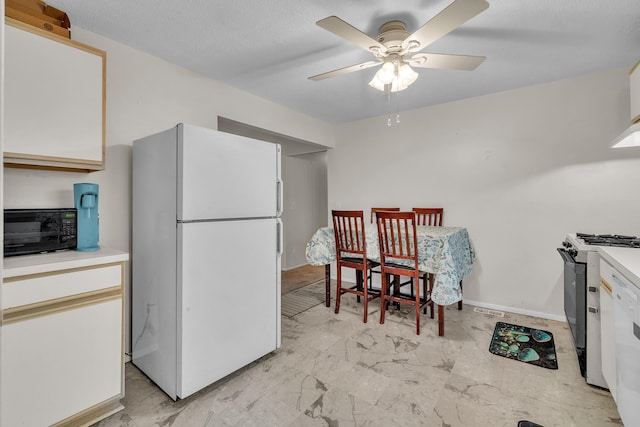 kitchen featuring gas range, white cabinetry, ceiling fan, and white refrigerator