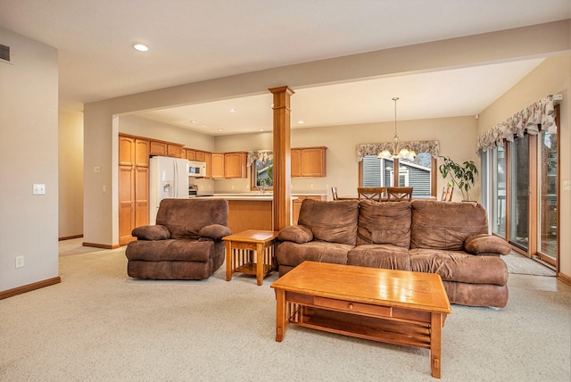 carpeted living room with decorative columns and a notable chandelier