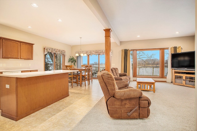 living room featuring light carpet, an inviting chandelier, a healthy amount of sunlight, and ornate columns