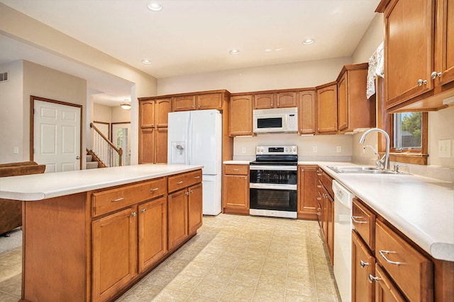 kitchen featuring a breakfast bar, a center island, white appliances, and sink