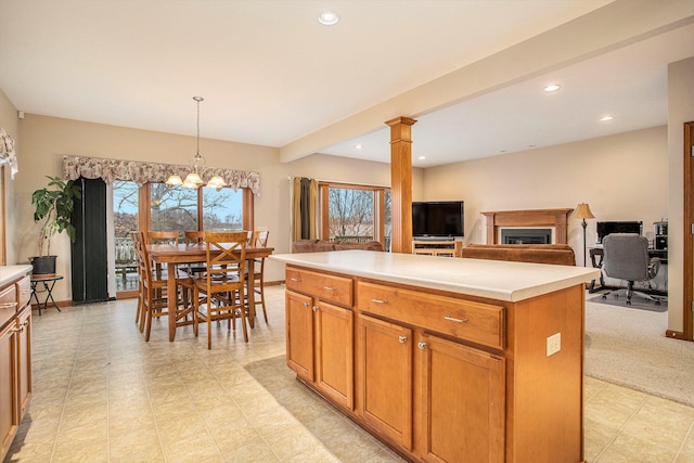 kitchen with pendant lighting, a center island, an inviting chandelier, ornate columns, and light colored carpet