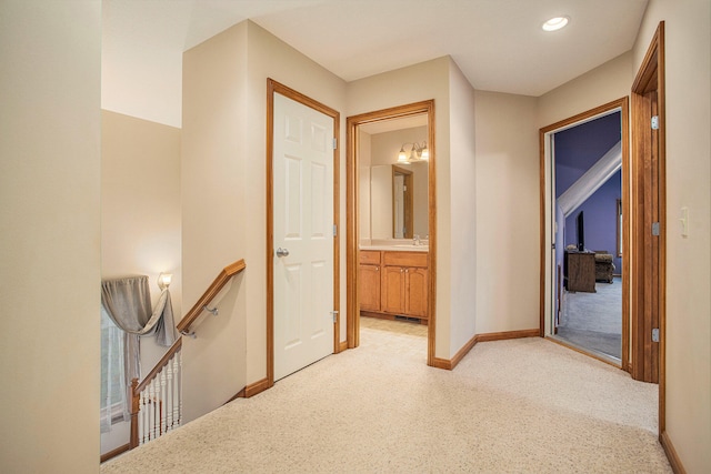 hallway with light carpet and sink