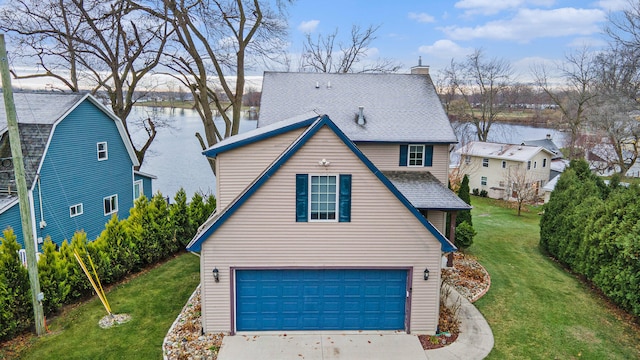 view of front of home featuring a front lawn, a water view, and a garage