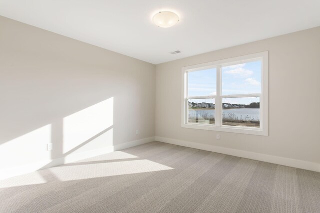 spare room with light carpet and a water view