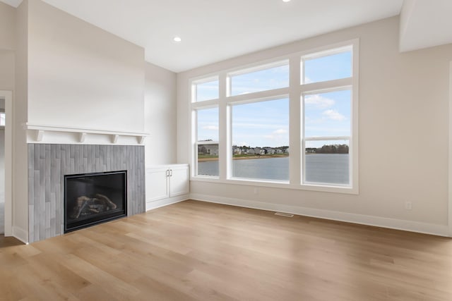 unfurnished living room with a water view and light hardwood / wood-style flooring