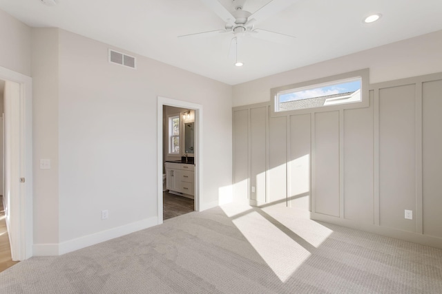 unfurnished bedroom with light colored carpet, ceiling fan, and ensuite bathroom