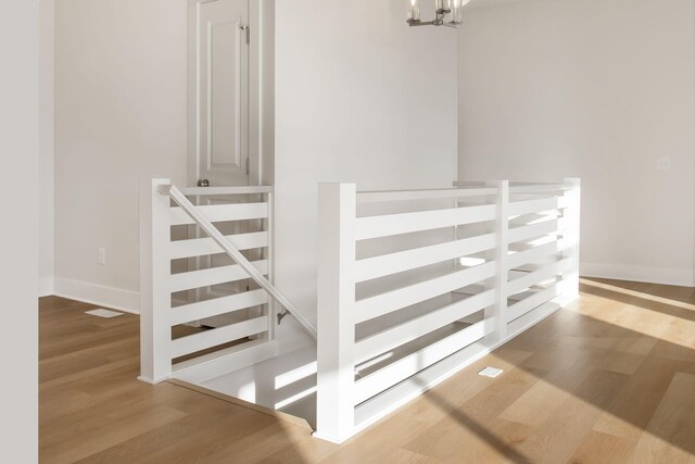 stairs featuring wood-type flooring and a notable chandelier