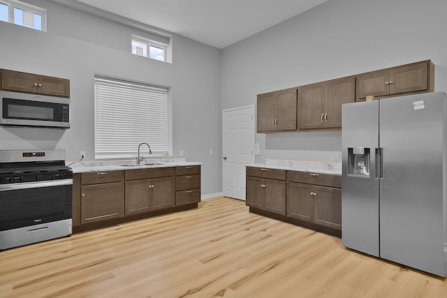 7564 13 Mile Rd NE, Rockford, MI 49341 - kitchen with sink, light hardwood / wood-style flooring, a towering ceiling, appliances with stainless steel finishes, and dark brown cabinetry