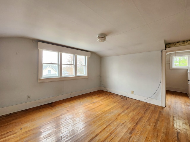 spare room with light wood-type flooring and lofted ceiling