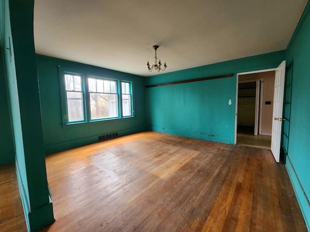 unfurnished room with a chandelier and wood-type flooring