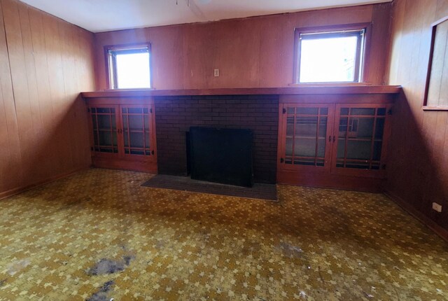 unfurnished living room featuring a fireplace and wooden walls