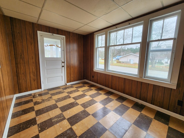 foyer entrance with a paneled ceiling, a wealth of natural light, and wooden walls