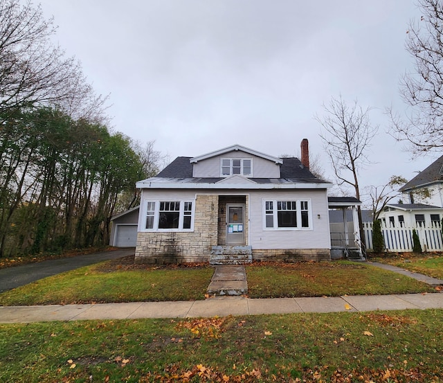 bungalow-style home featuring a garage, an outbuilding, and a front lawn