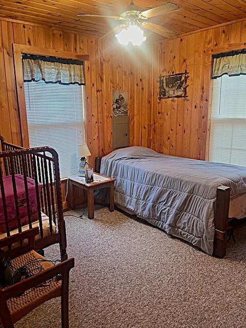 bedroom with ceiling fan, wood walls, wood ceiling, and carpet floors