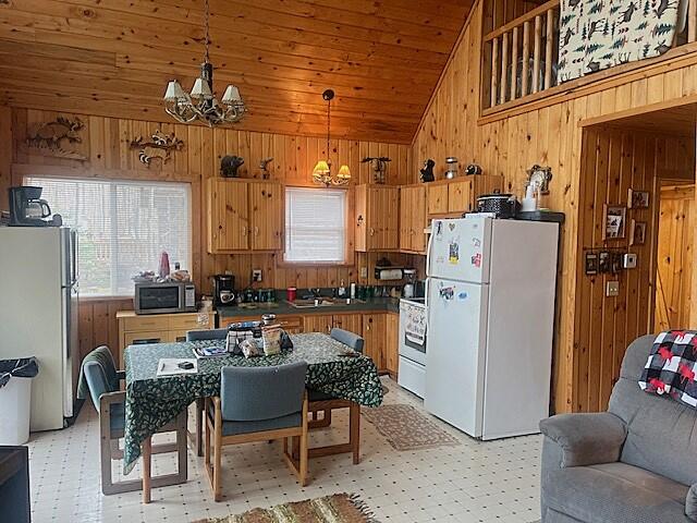 kitchen featuring a chandelier, appliances with stainless steel finishes, decorative light fixtures, and wood walls