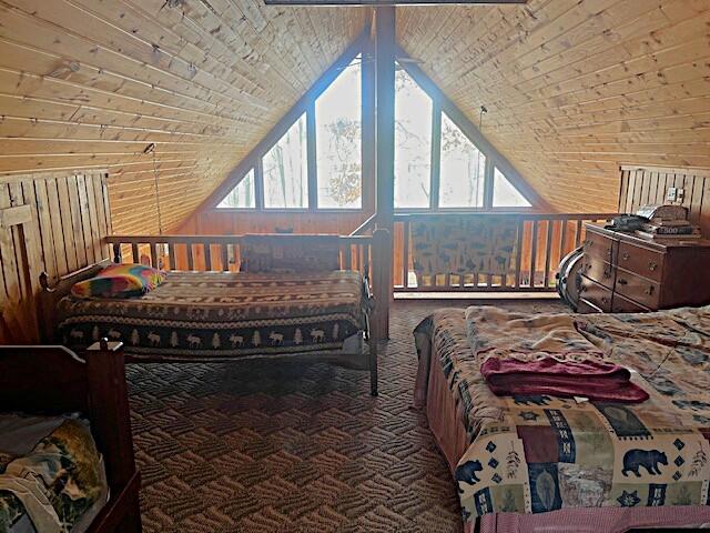 bedroom featuring wooden walls and vaulted ceiling