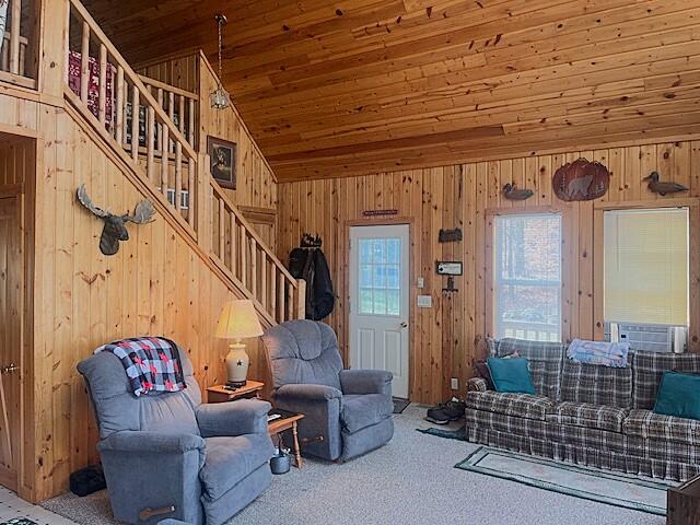 carpeted living room featuring cooling unit, wood walls, wood ceiling, and vaulted ceiling