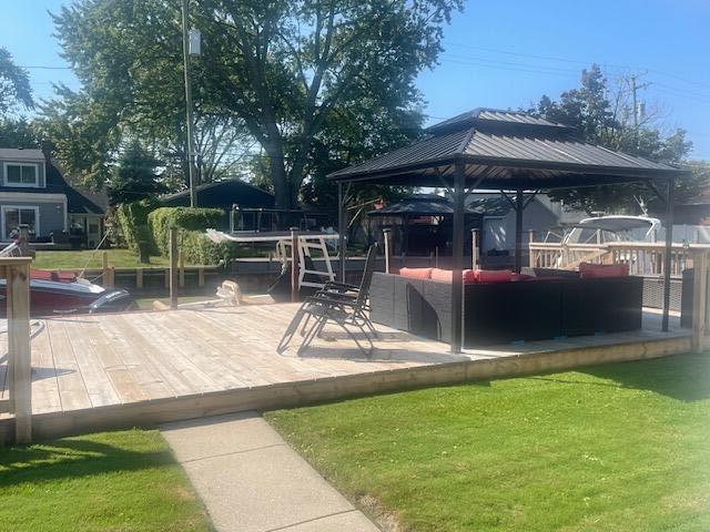 deck with a gazebo, an outdoor living space, and a yard