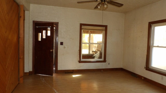 spare room with a wealth of natural light, ceiling fan, and hardwood / wood-style flooring