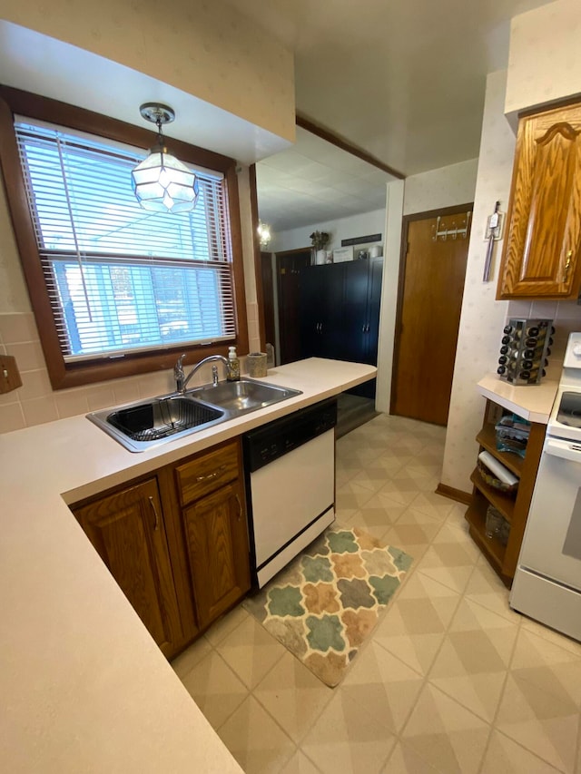 kitchen featuring white appliances, backsplash, hanging light fixtures, and sink