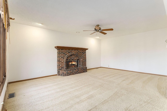 unfurnished living room with carpet flooring, a brick fireplace, and ceiling fan