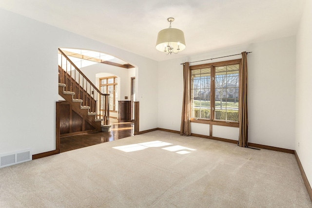 carpeted empty room featuring a chandelier