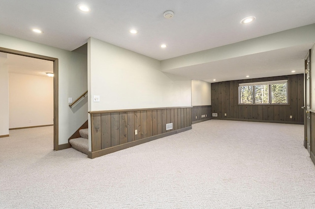 basement featuring light carpet and wooden walls