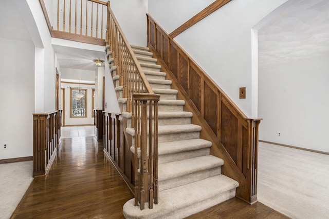 staircase featuring a high ceiling and hardwood / wood-style flooring