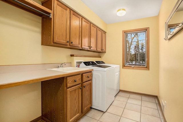 clothes washing area featuring cabinets, light tile patterned floors, washing machine and dryer, and sink