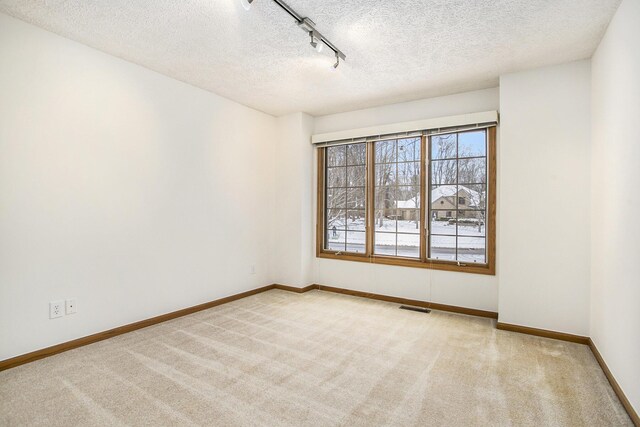 carpeted empty room with a textured ceiling and track lighting